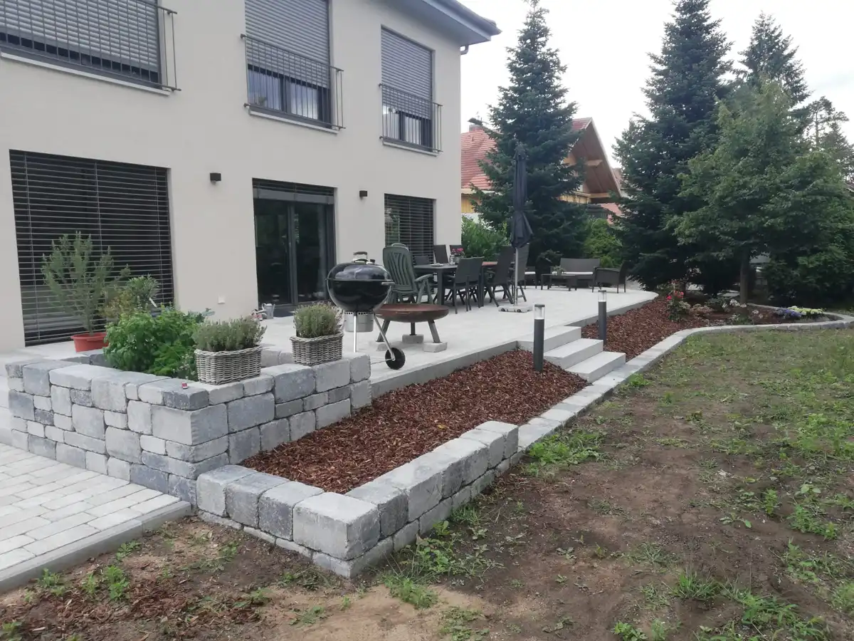 Von Pool-GaLa-Bau Mitschke gestaltete Außenanlage mit Pflasterflächen und Natursteinmauern